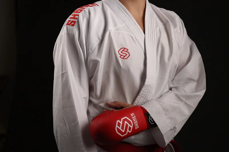 Atleta com o kimono Shomen a segurar uma luva vermelha