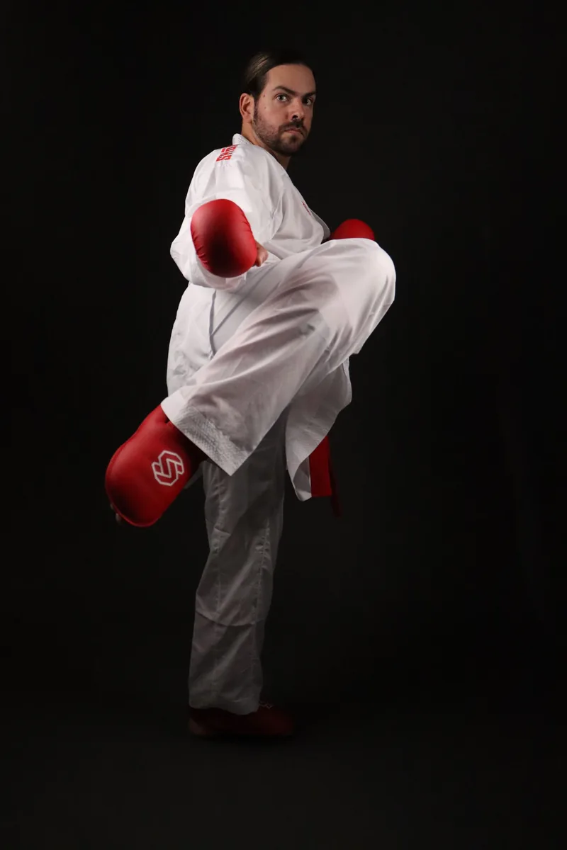 Atleta a executar um pontapé com o kimono de kumite Shomen