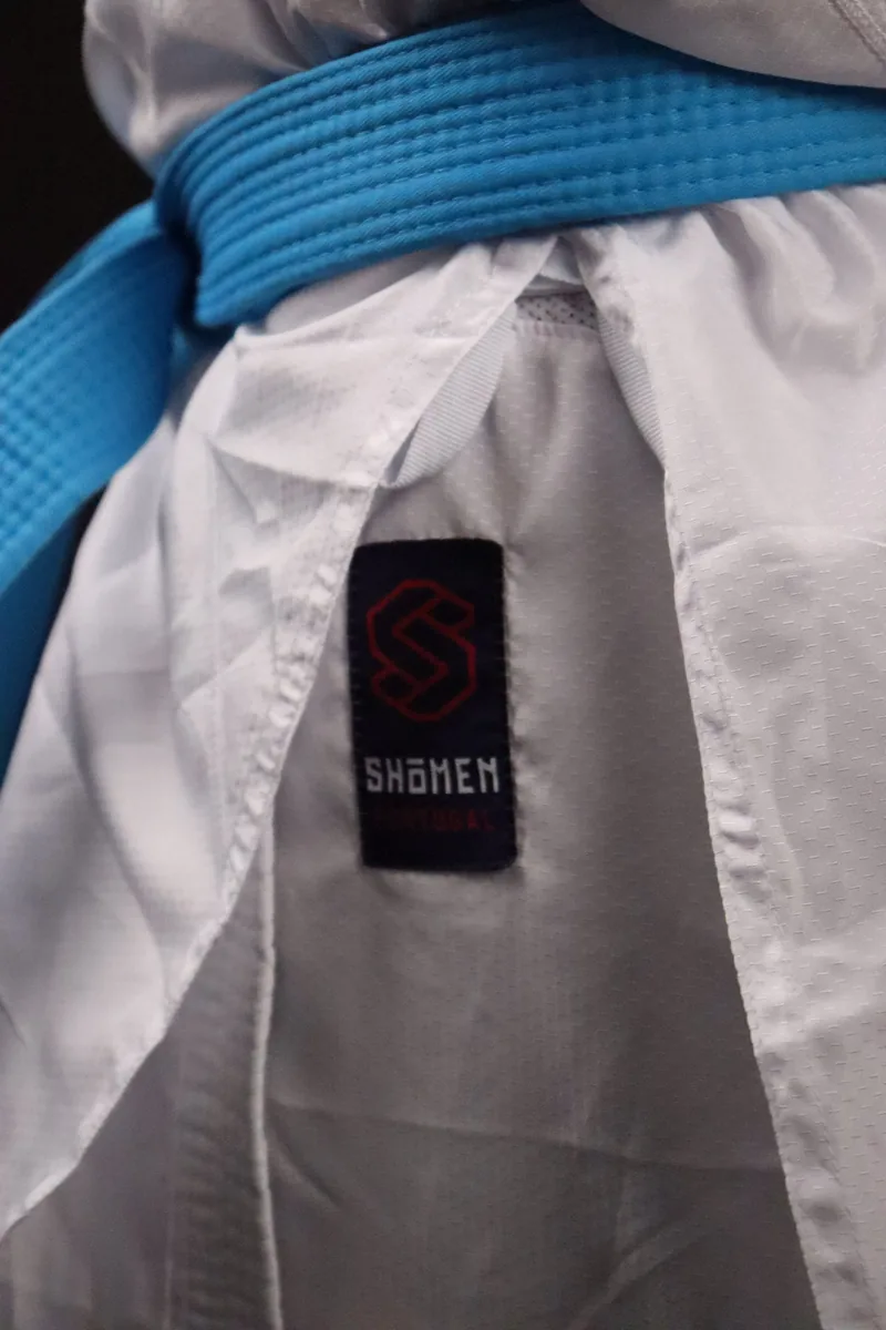 Cinto azul Shomen atado sobre o kimono, com a etiqueta visível