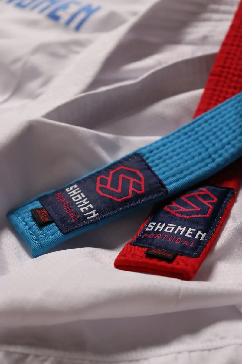 Cintos de kumite azul e vermelho Shomen sobre um kimono branco