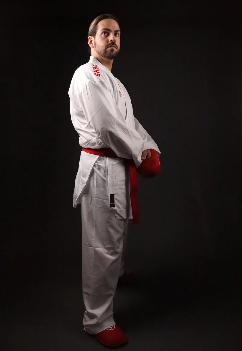 Atleta de perfil com o kimono de kumite Shomen, cinto vermelho e luvas vermelhas